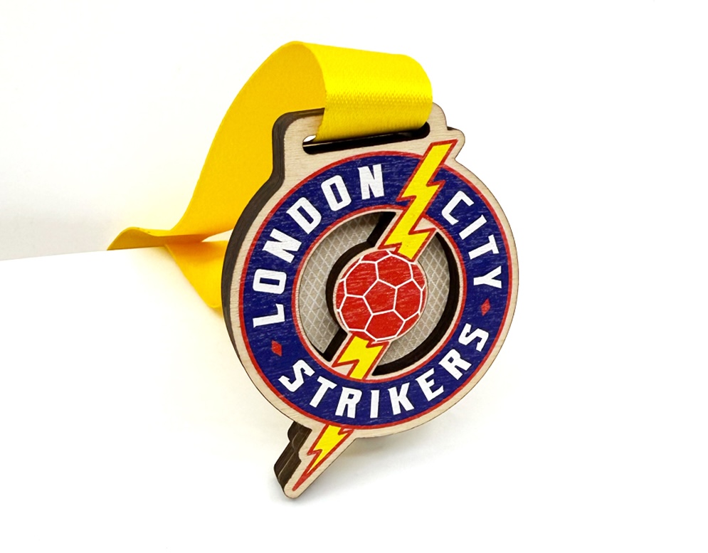 Colourful wooden football medal with lightning bolt design and yellow ribbon for London City Strikers.