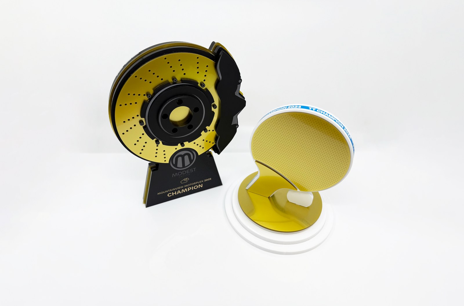 A matching pair of bespoke custom-shaped awards in gold and black, designed as one family